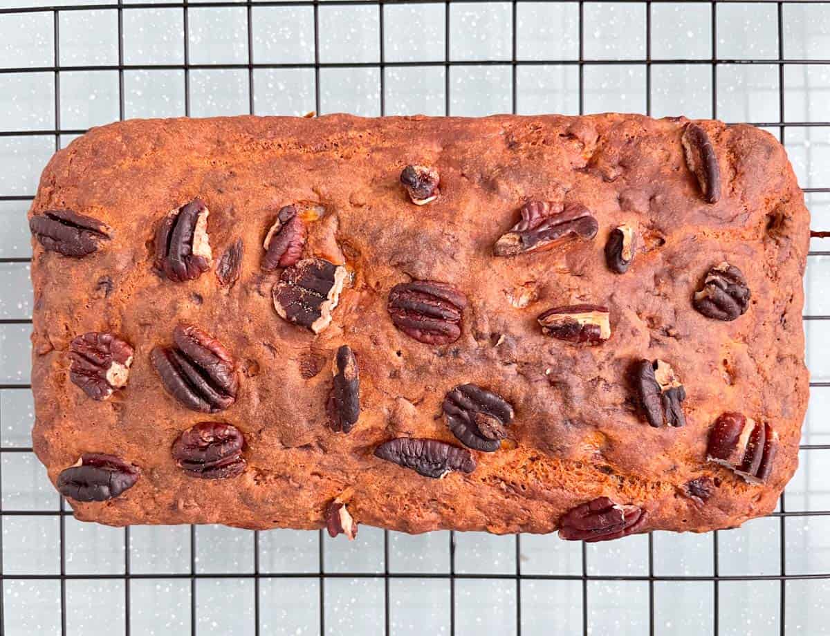 Baked banana bread loaf topped with chopped nuts.
