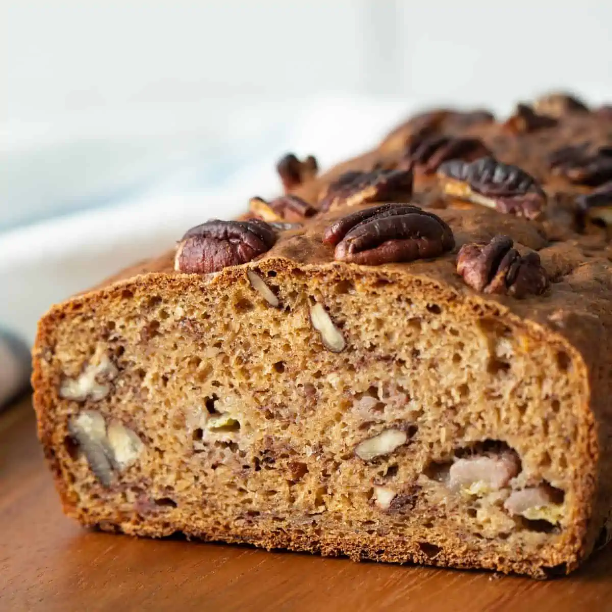 Banana bread loaf topped with chopped nuts. 
