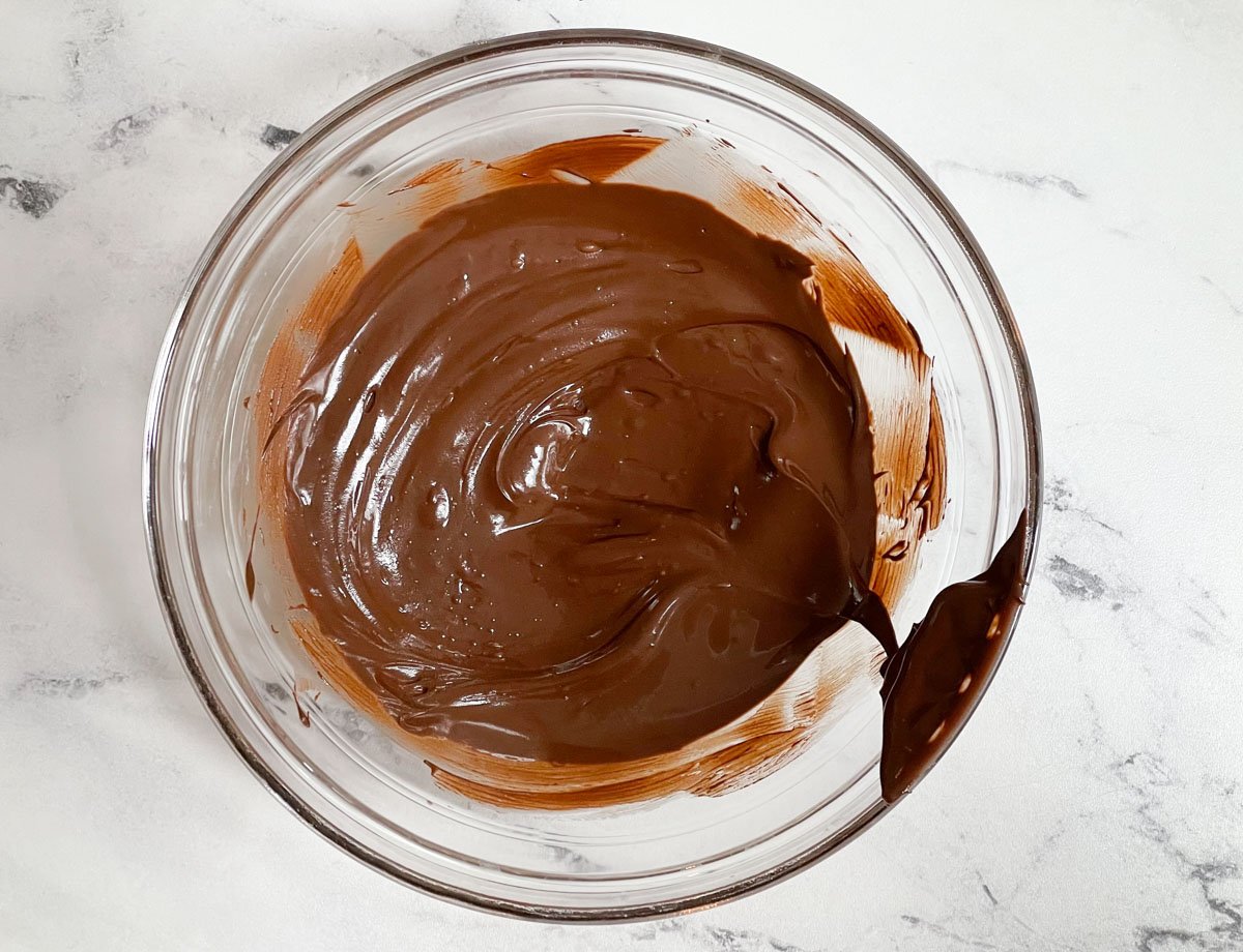 Melted dark chocolate in glass mixing bowl.
