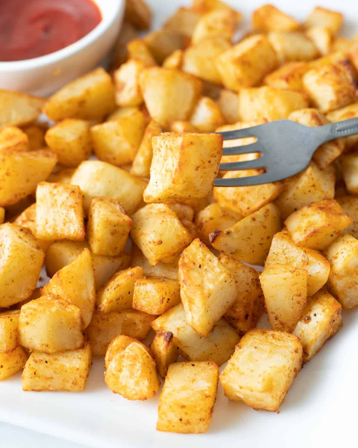 Platter of air fryer home fries, with one bite on a fork.
