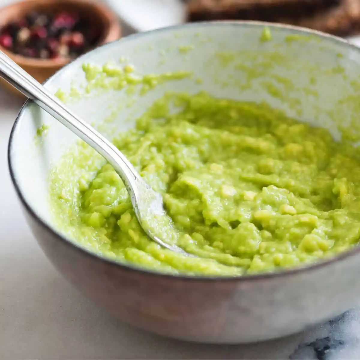 Mashed avocado in bowl with fork.
