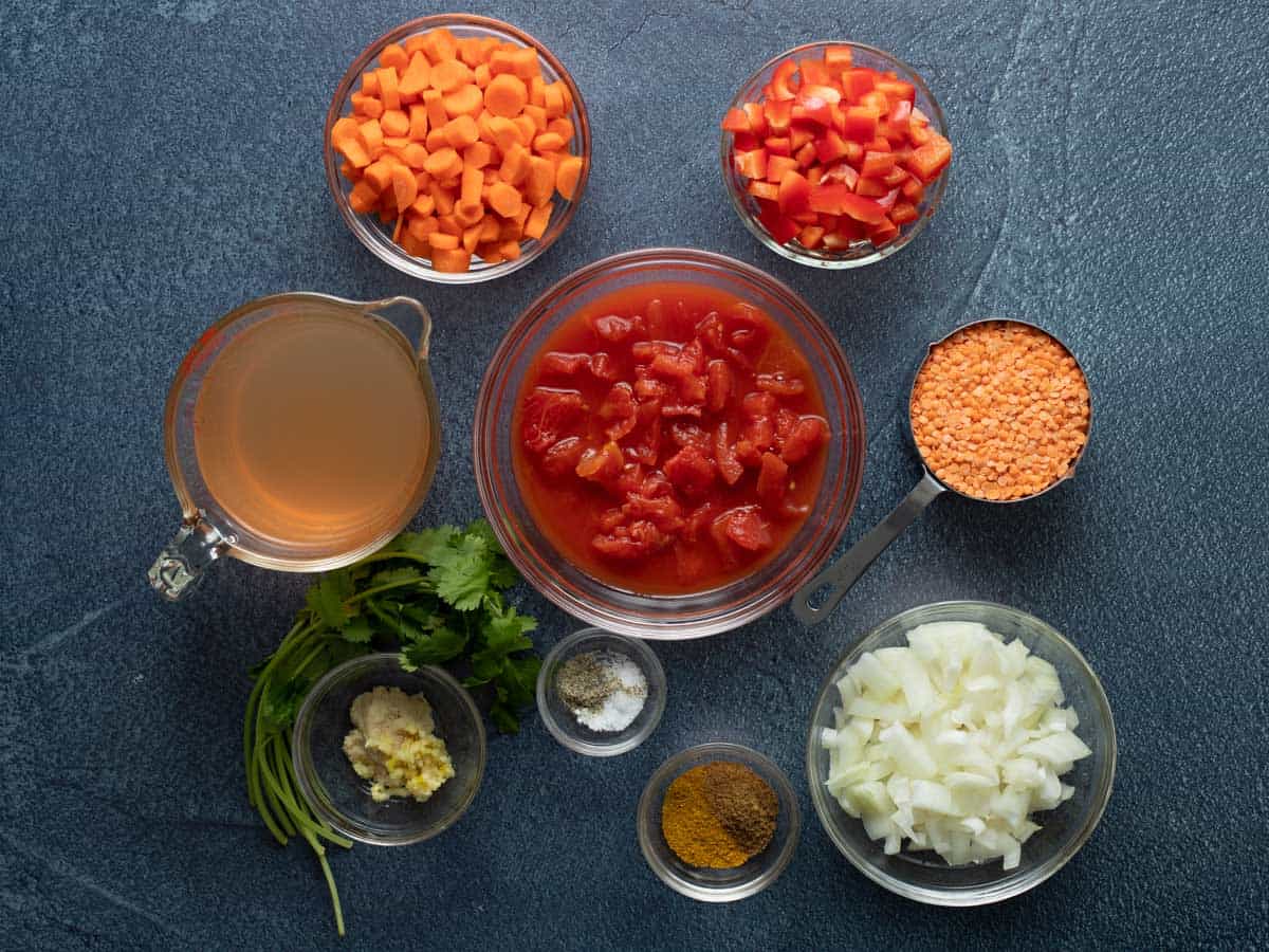 Vegan lentil curry ingredients: carrots, red peppers, lentils, diced tomatoes, diced onion, curry and cumin, salt and pepper, garlic and ginger, cilantro, vegetable broth. 
