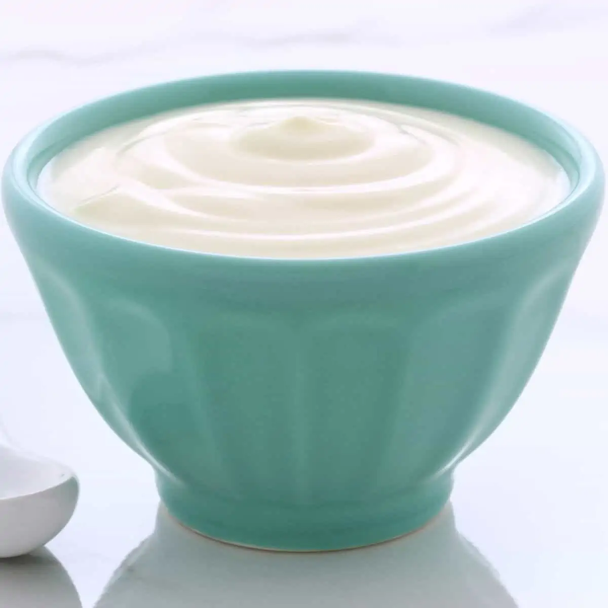 Creamy plain yogurt in turquoise bowl.
