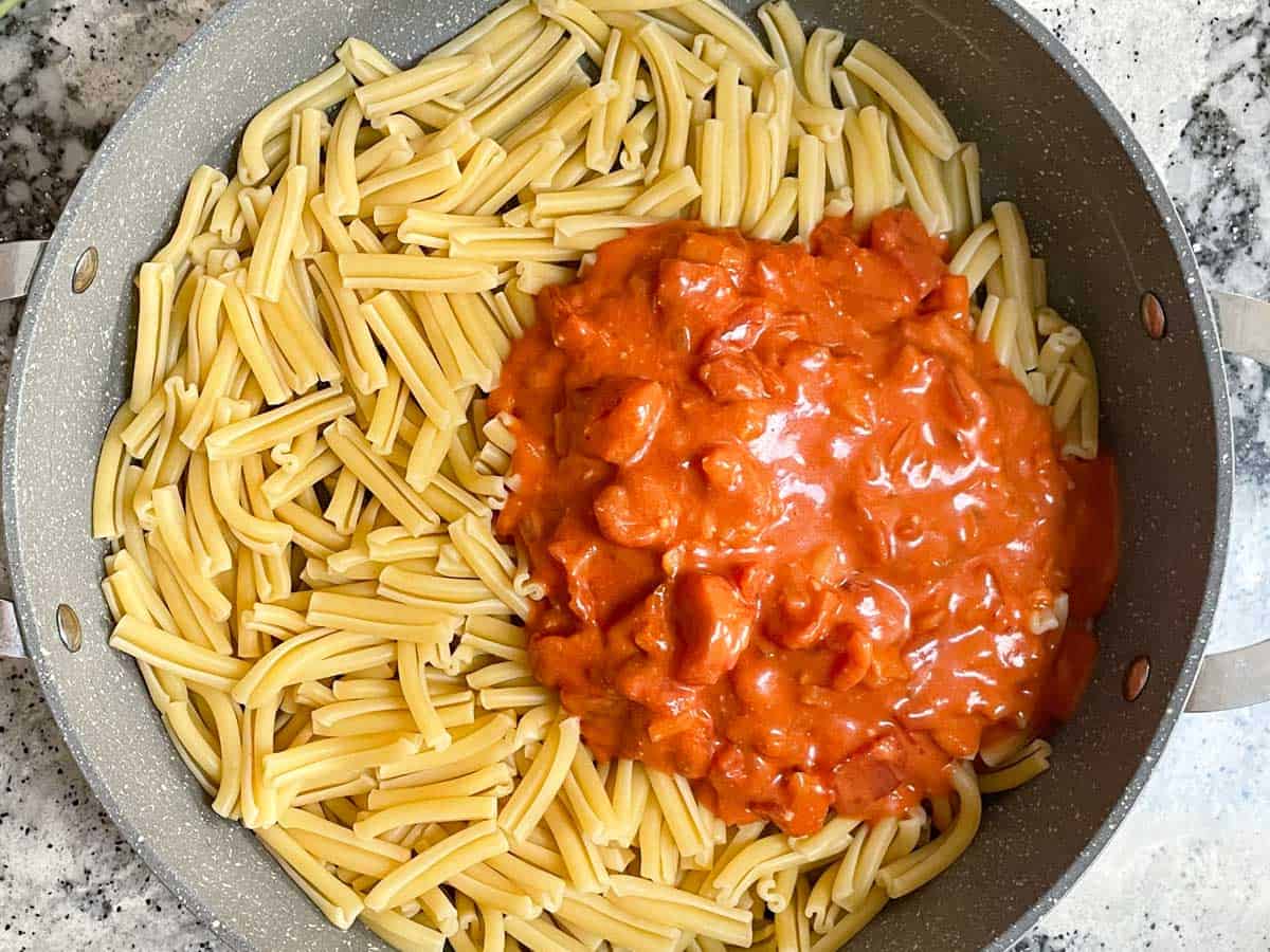 Adding creamy tomato sauce to casarecce pasta.
