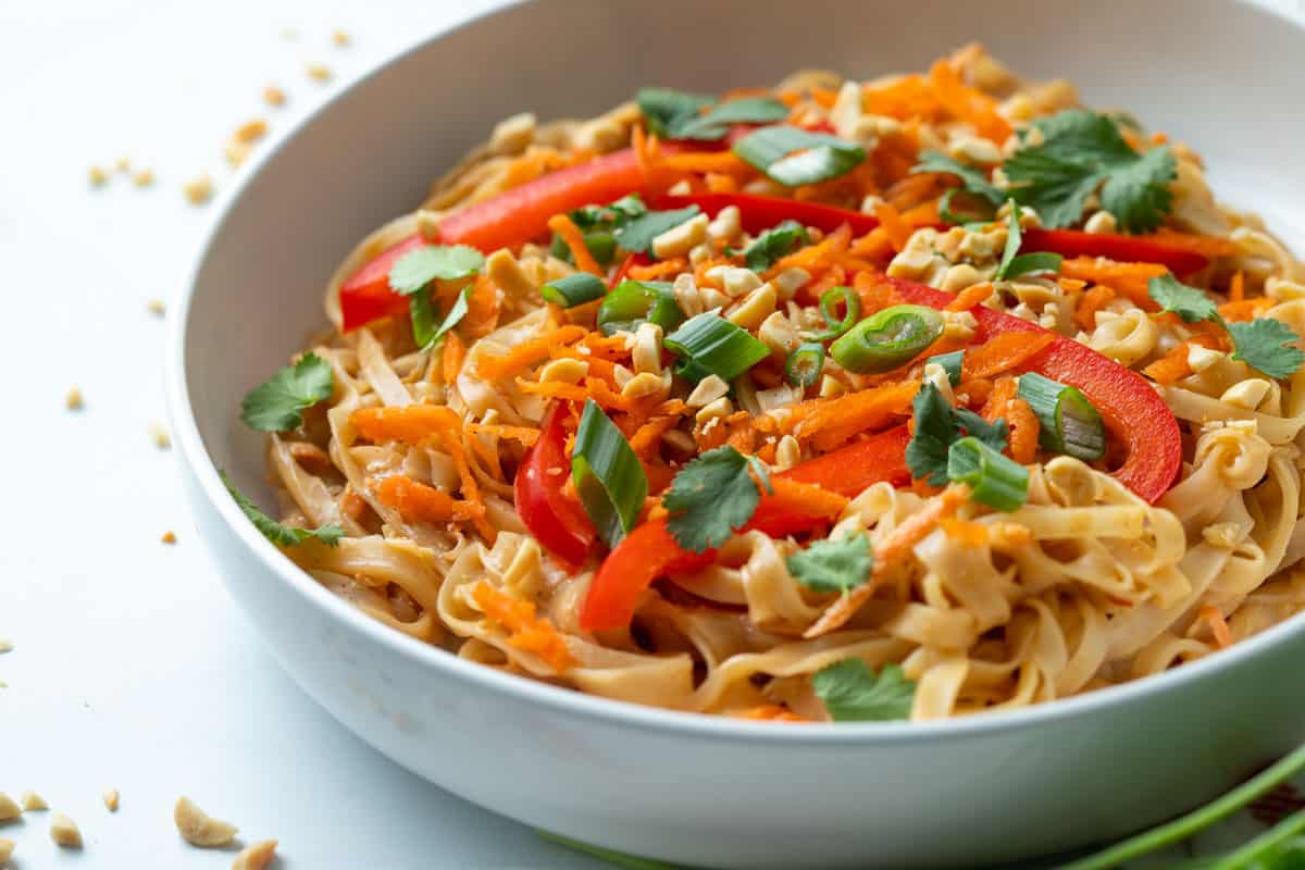 Bowl of Thai Peanut Noodles topped with fresh vegetables.
