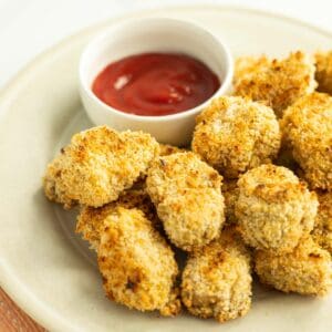 Tofu chicken nuggets on serving plate served with a side of ketchup.