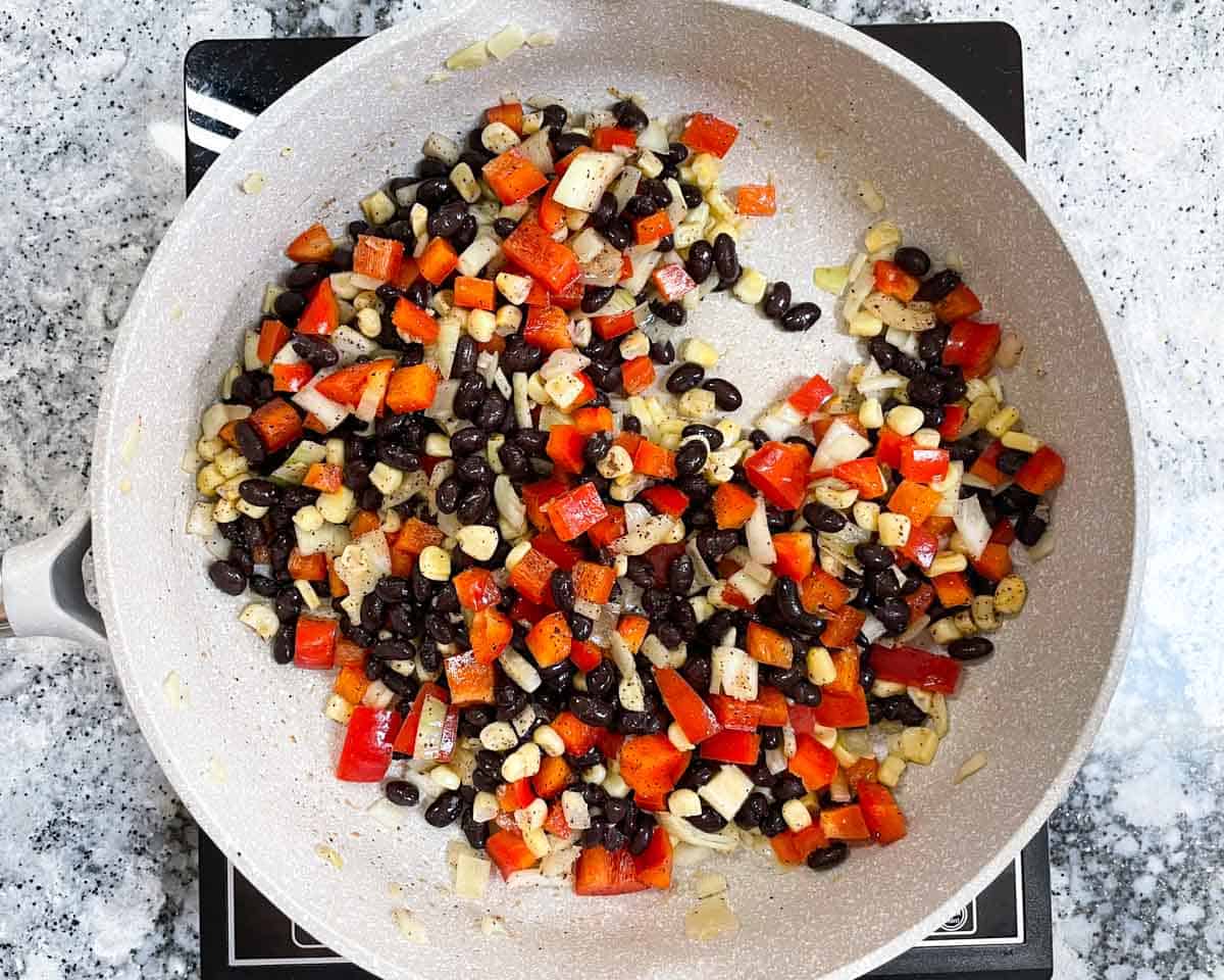Black beans, onions, corn, and red peppers in saute pan.
