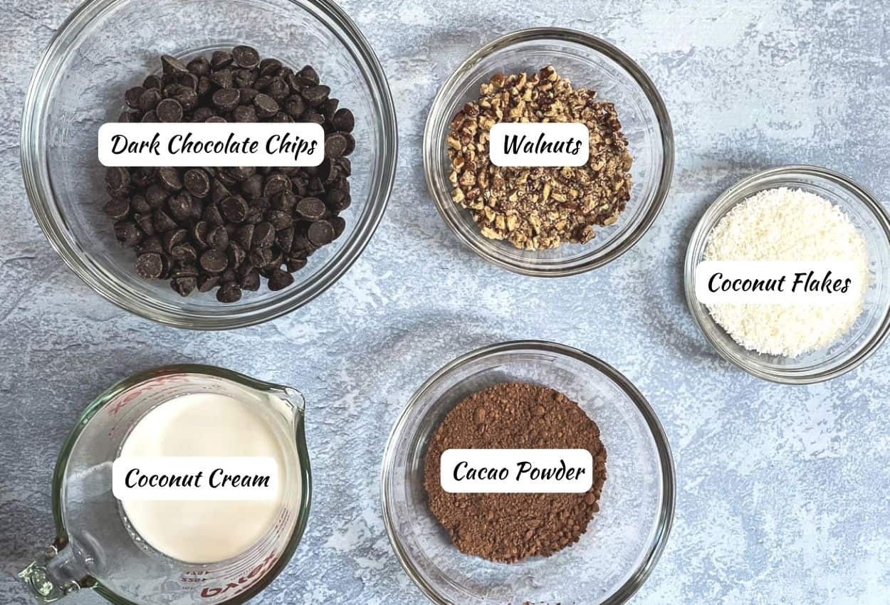 Vegan truffle ingredients: dark chocolate chips, coconut cream, cacao powder, walnuts, coconut flakes.