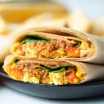 Vegan breakfast burrito on black plate.