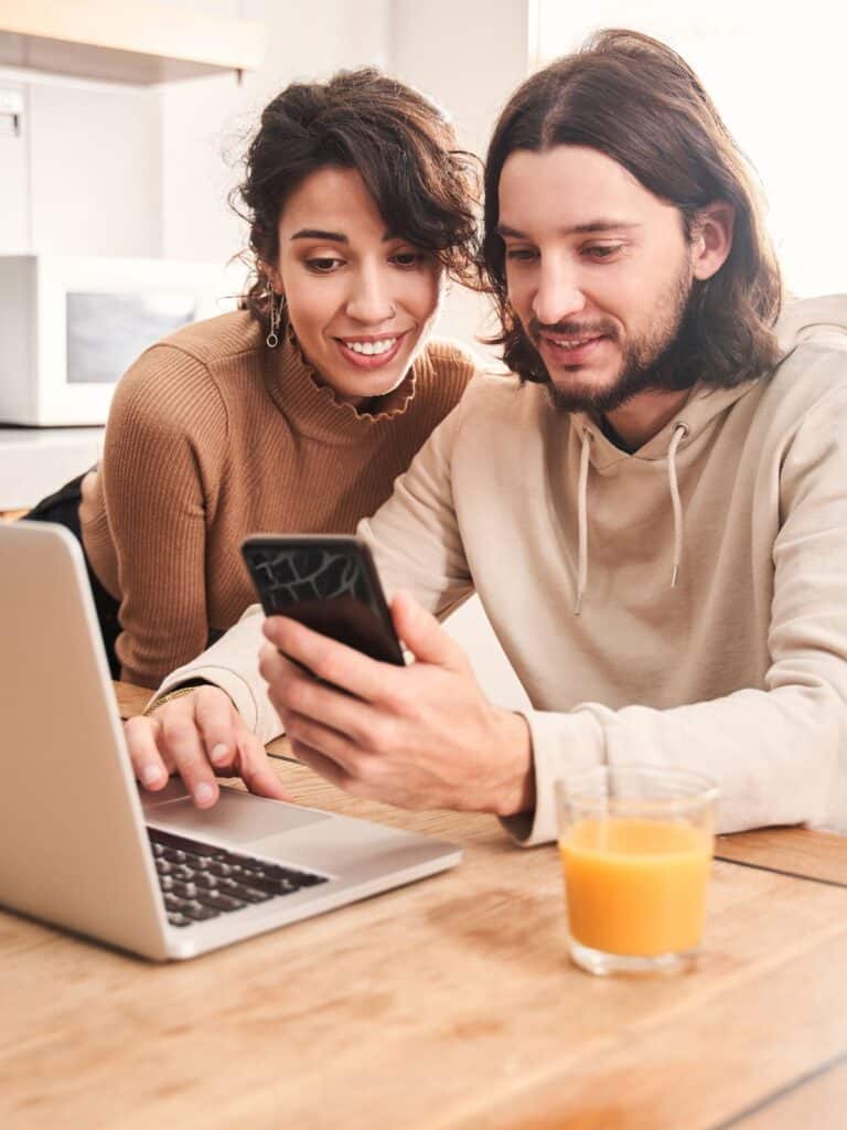 Man and women looking at computer and phone.

