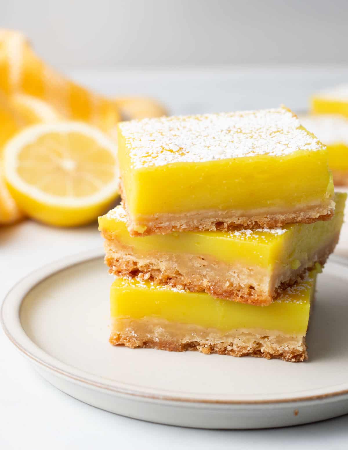Stack of three lemon bars on a white plate.
