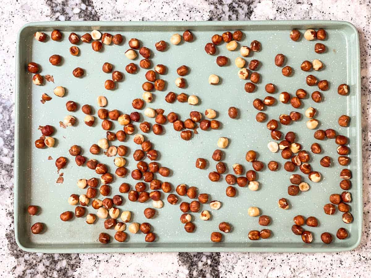 Hazelnuts spread on baking sheet.
