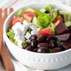 Vegan greek salad in a white bowl.