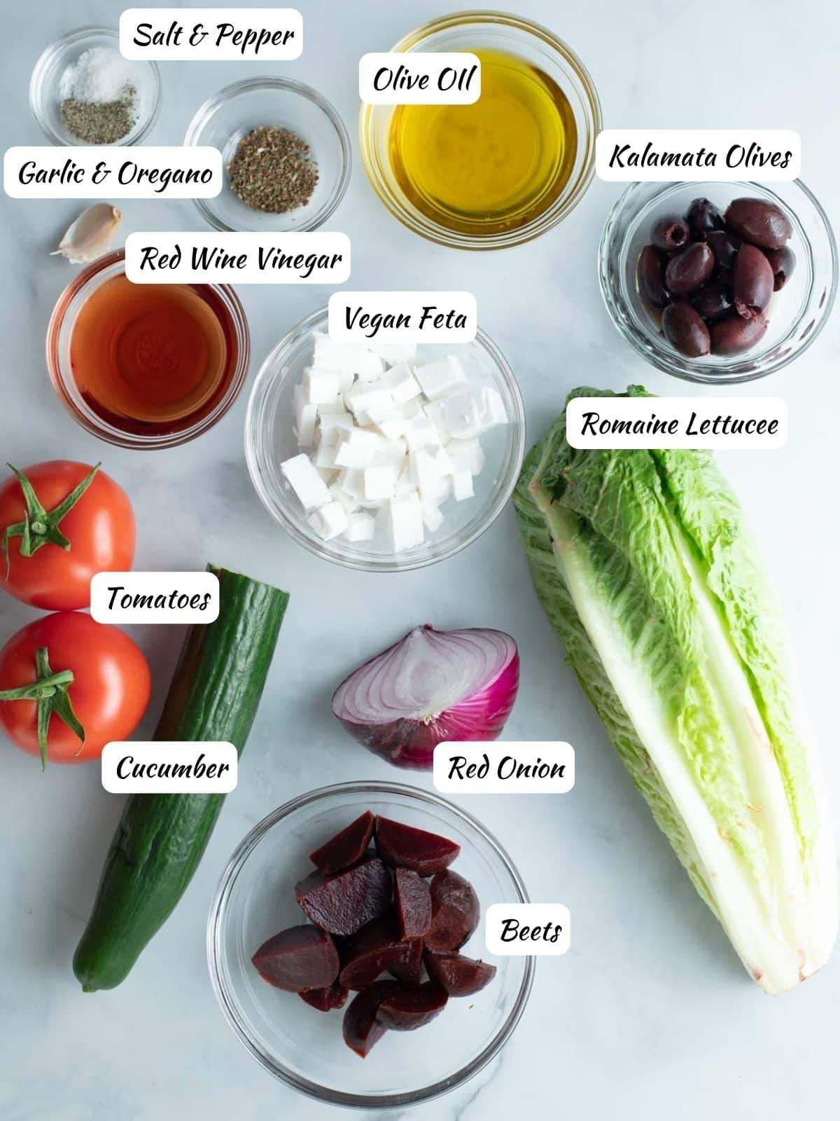 Vegan Greek Salad Ingredients: salt, pepper, oregano, olive oil, garlic, kalamata olives, romaine lettuce, beets, red onion, vegan feta, cucumber, tomatoes. 
