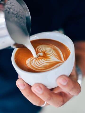 Man pouring milk into cup for a latte.