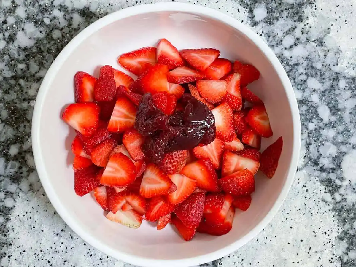 Sliced strawberries topped with raspberry jam.
