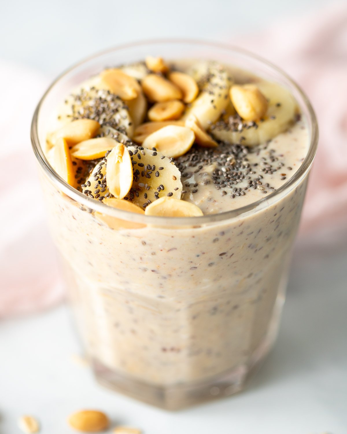 Glass filled with vegan peanut butter overnight oats. Topped with bananas.

