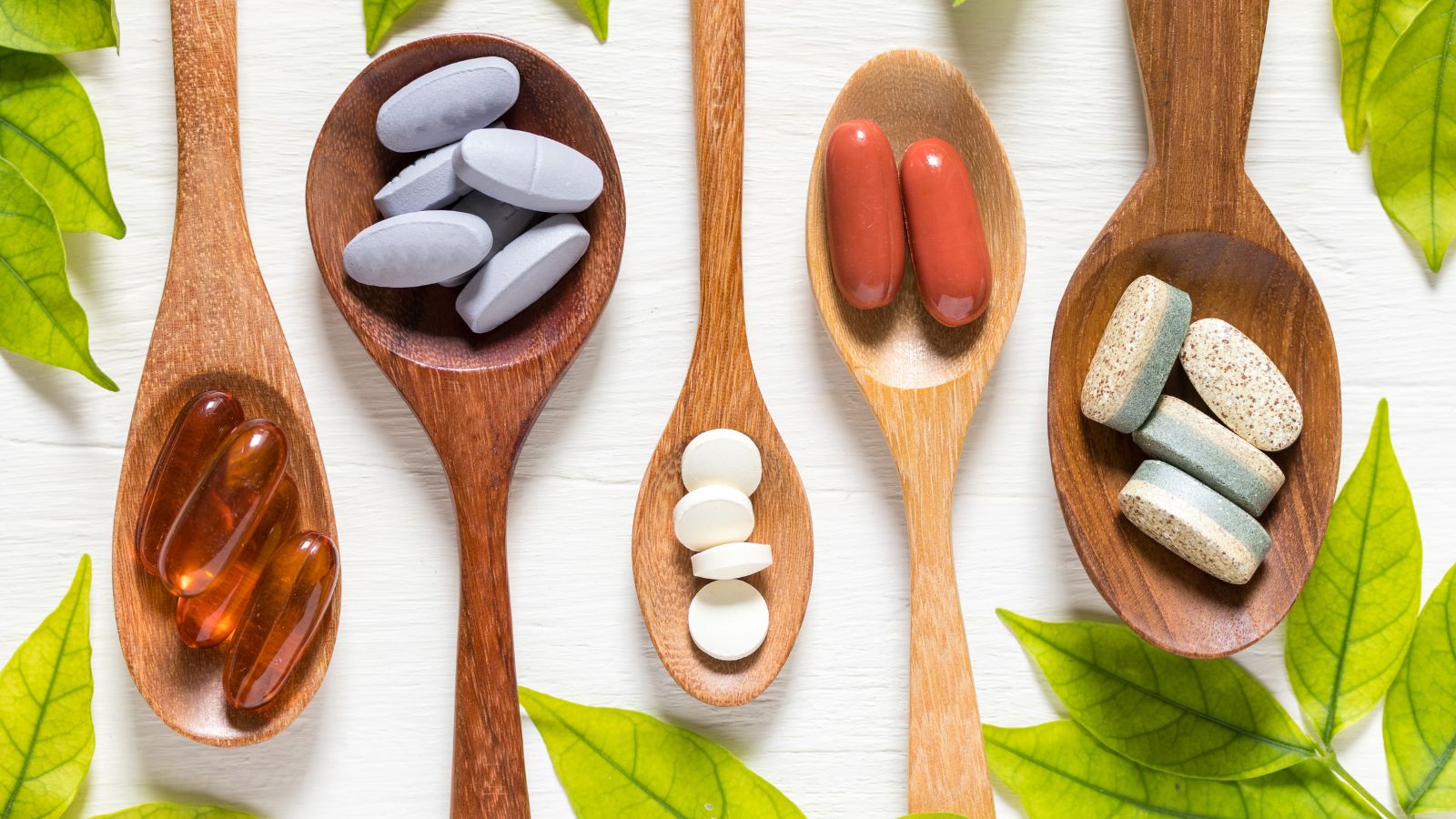Vitamins displayed on wood spoons.
