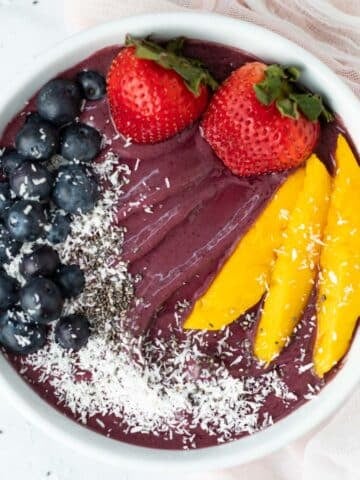 Acai bowl topped with fresh blueberries, strawberries, mango, coconut flakes, and chia seeds.
