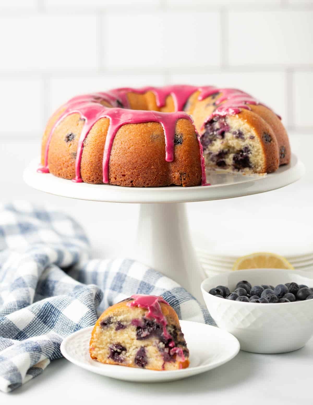 Vegan Blueberry bundt cake on a cake stand with a slice in front on a plate.
