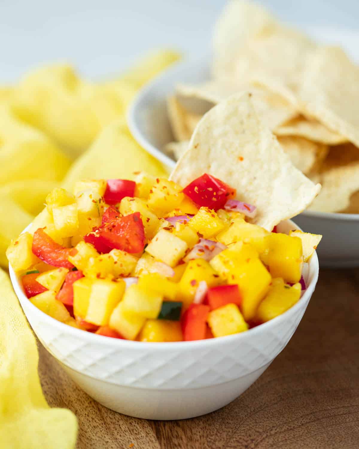 Pineapple mango salsa with a chip in the dip.
