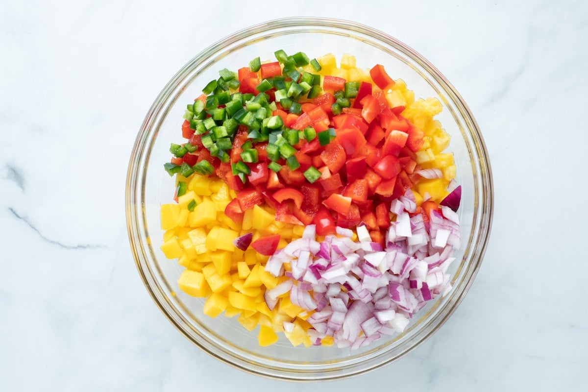 Pineapple mango salsa ingredients in a glass bowl.
