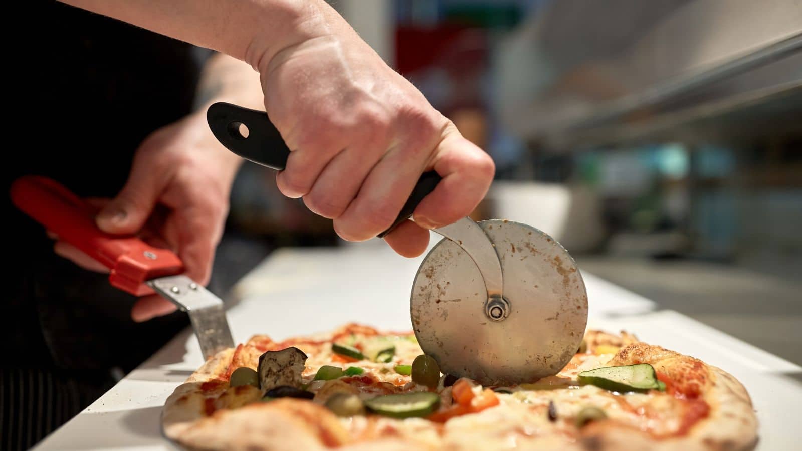 Cutting a pizza with a pizza cutter.