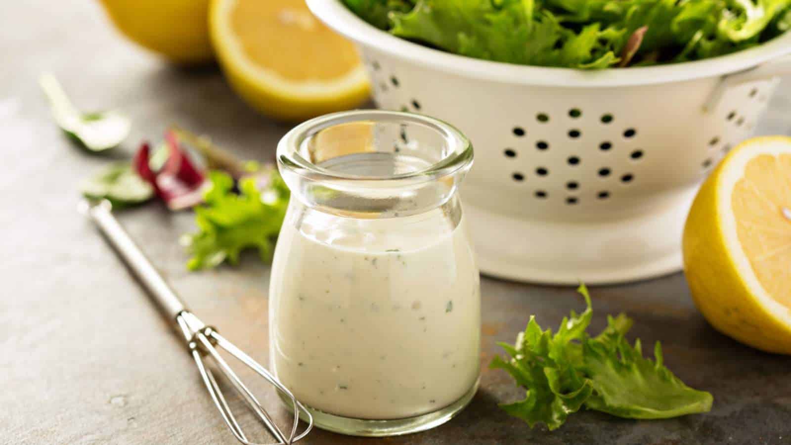 Ranch dressing in small jar beside salad bowl.
