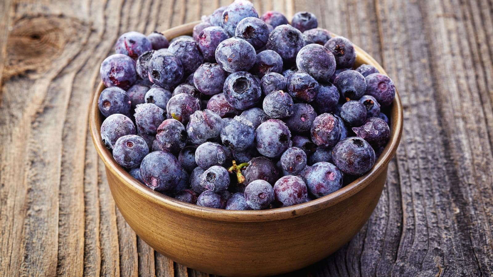 Frozen blueberries in a wooden bowl. 