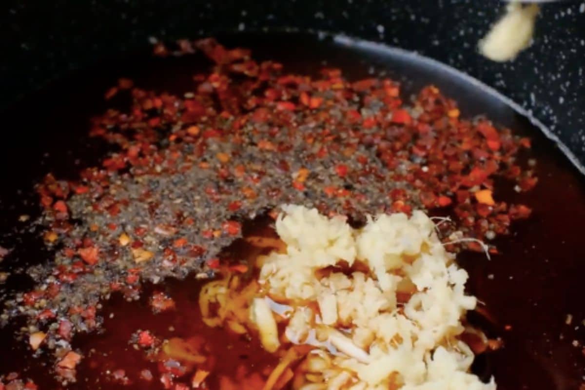Adding ginger to Korean BBQ sauce ingredients in a pot.
