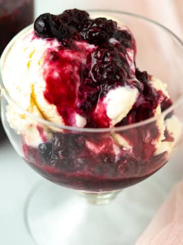 Berry compote on top of vanilla ice cream in a bowl.
