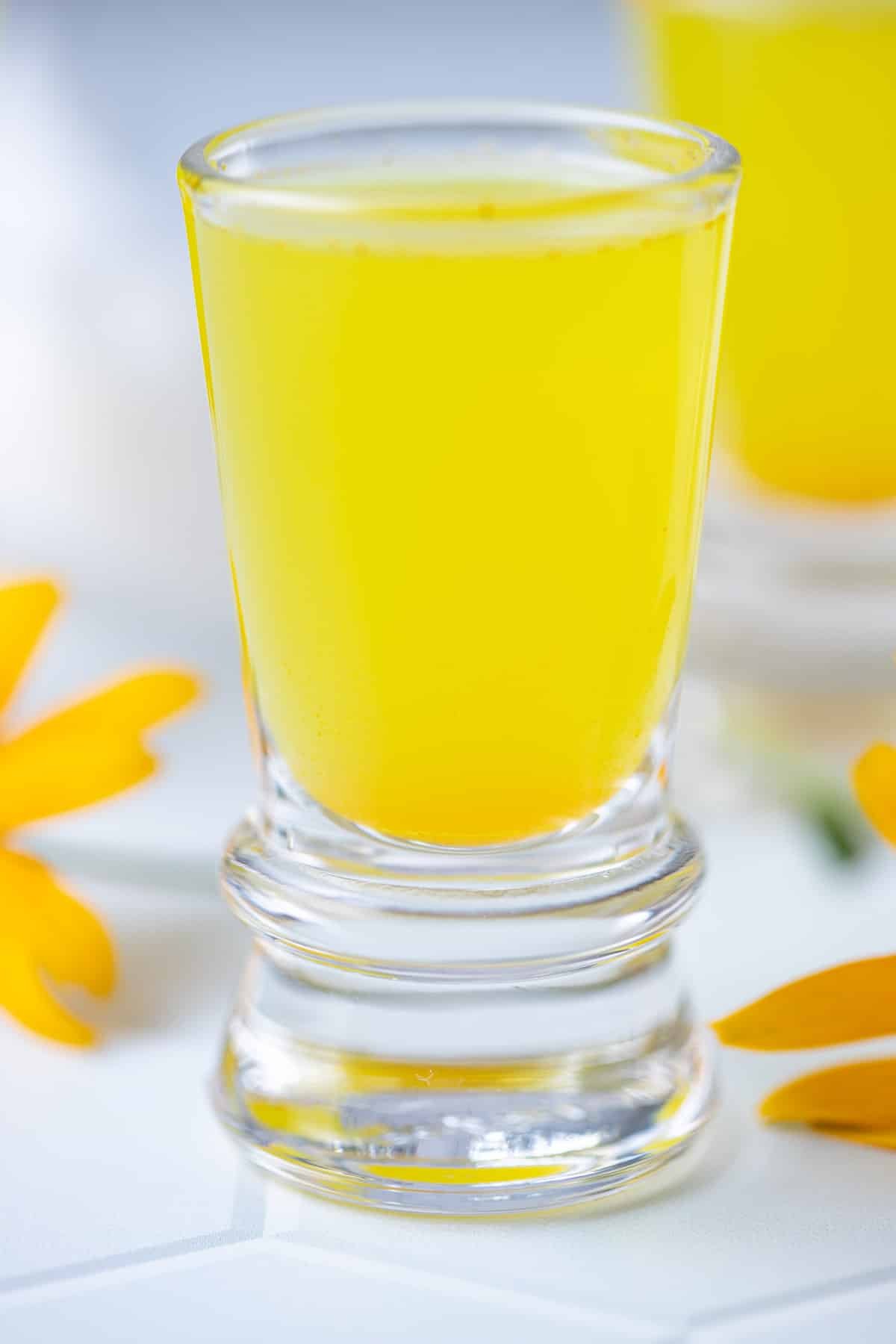 Close up of lemon ginger turmeric shot in shot glass.
