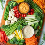 Veggie tray with assorted veggies and dip on a wood serving platter.
