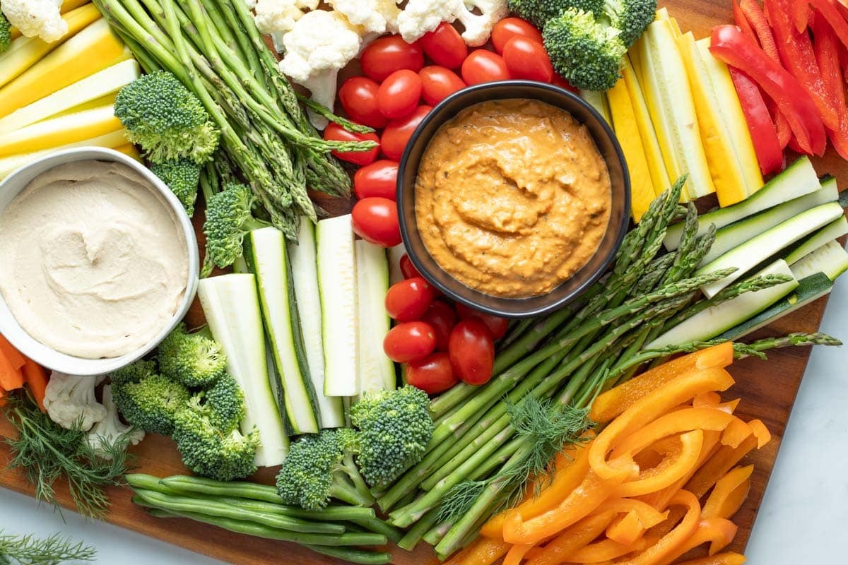 Overhead of veggie tray with two types of dips and assorted vegetables.
