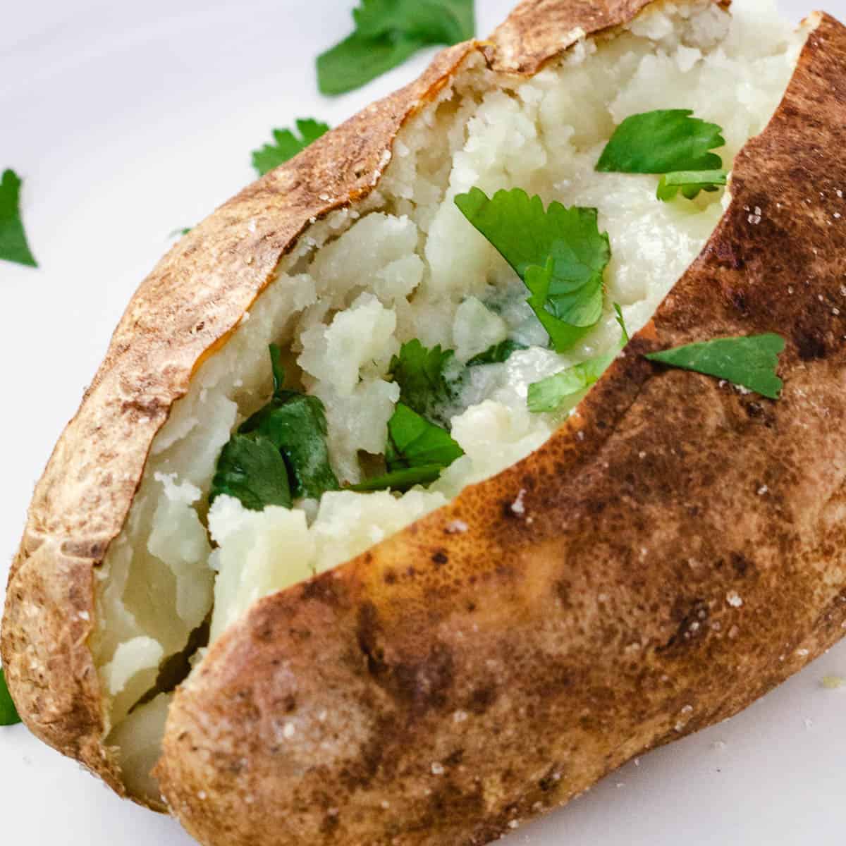 Baked potato with butter and fresh herbs.