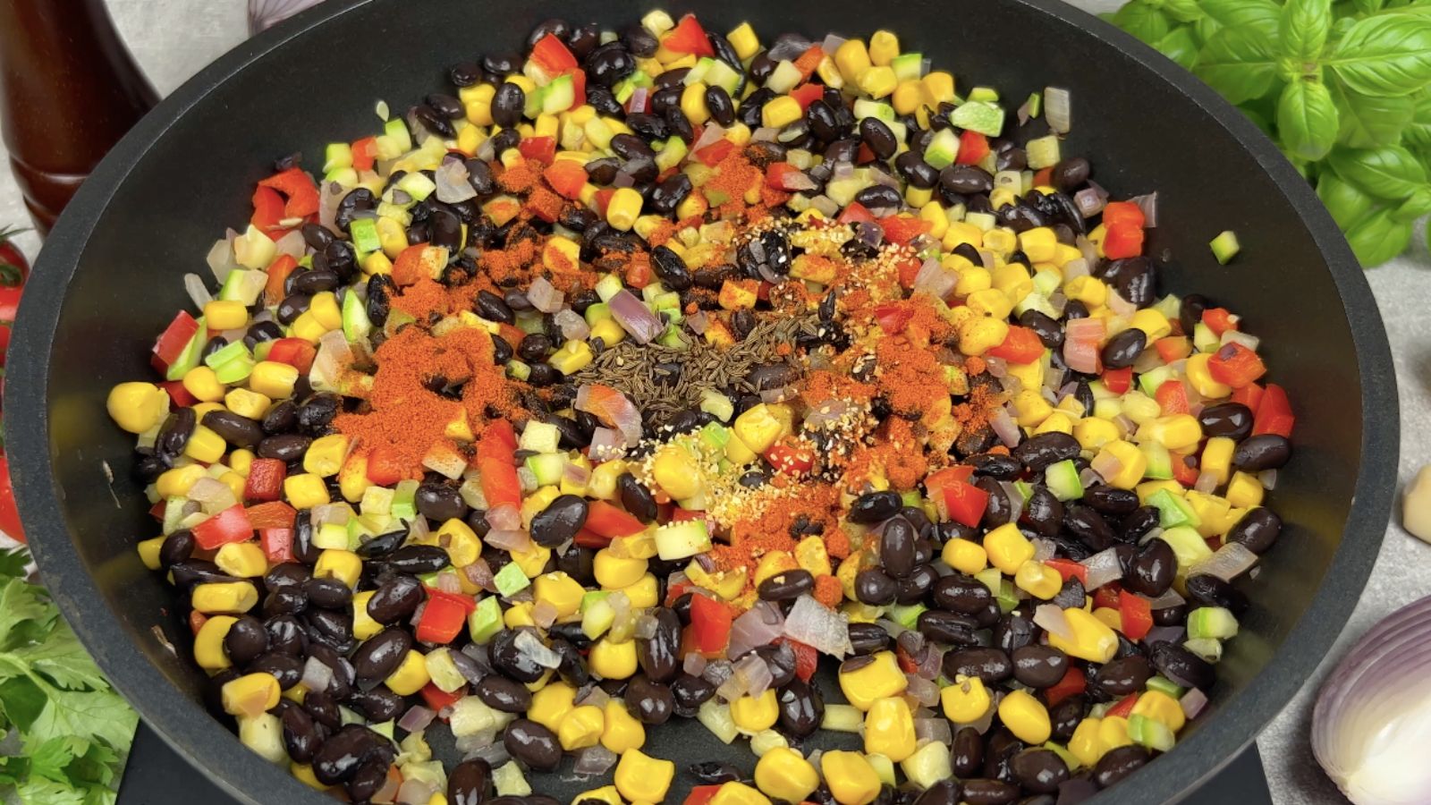 Black beans, corn, and vegetables in skillet with seasoning.
