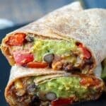 Vegan black bean burrito on a black plate.