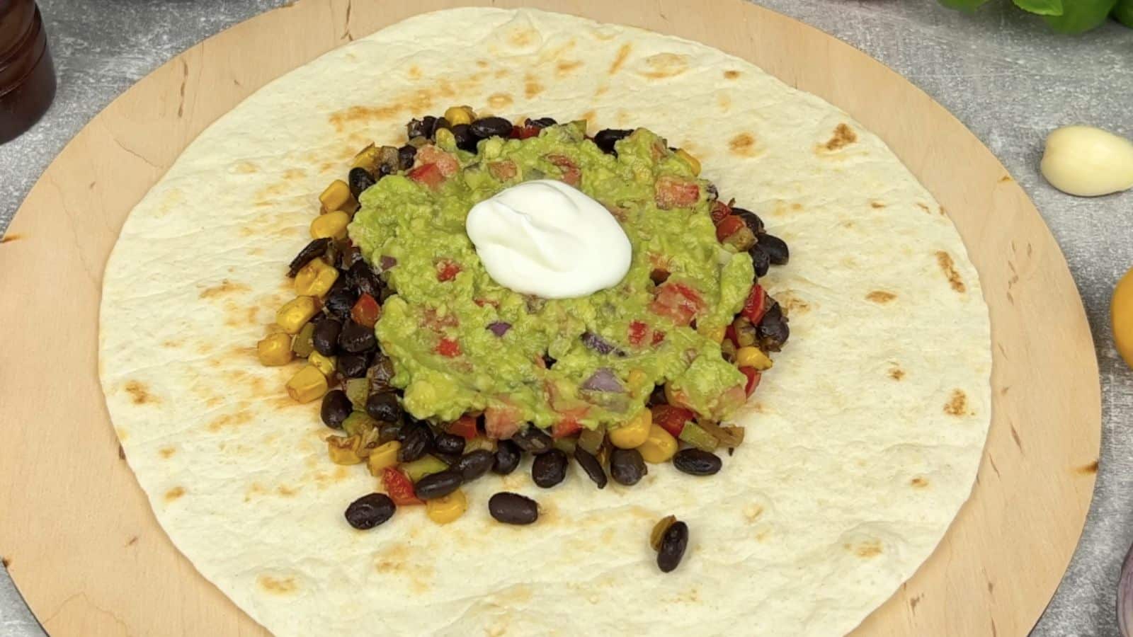 Filling burrito with beans, guacamole, and sour cream.