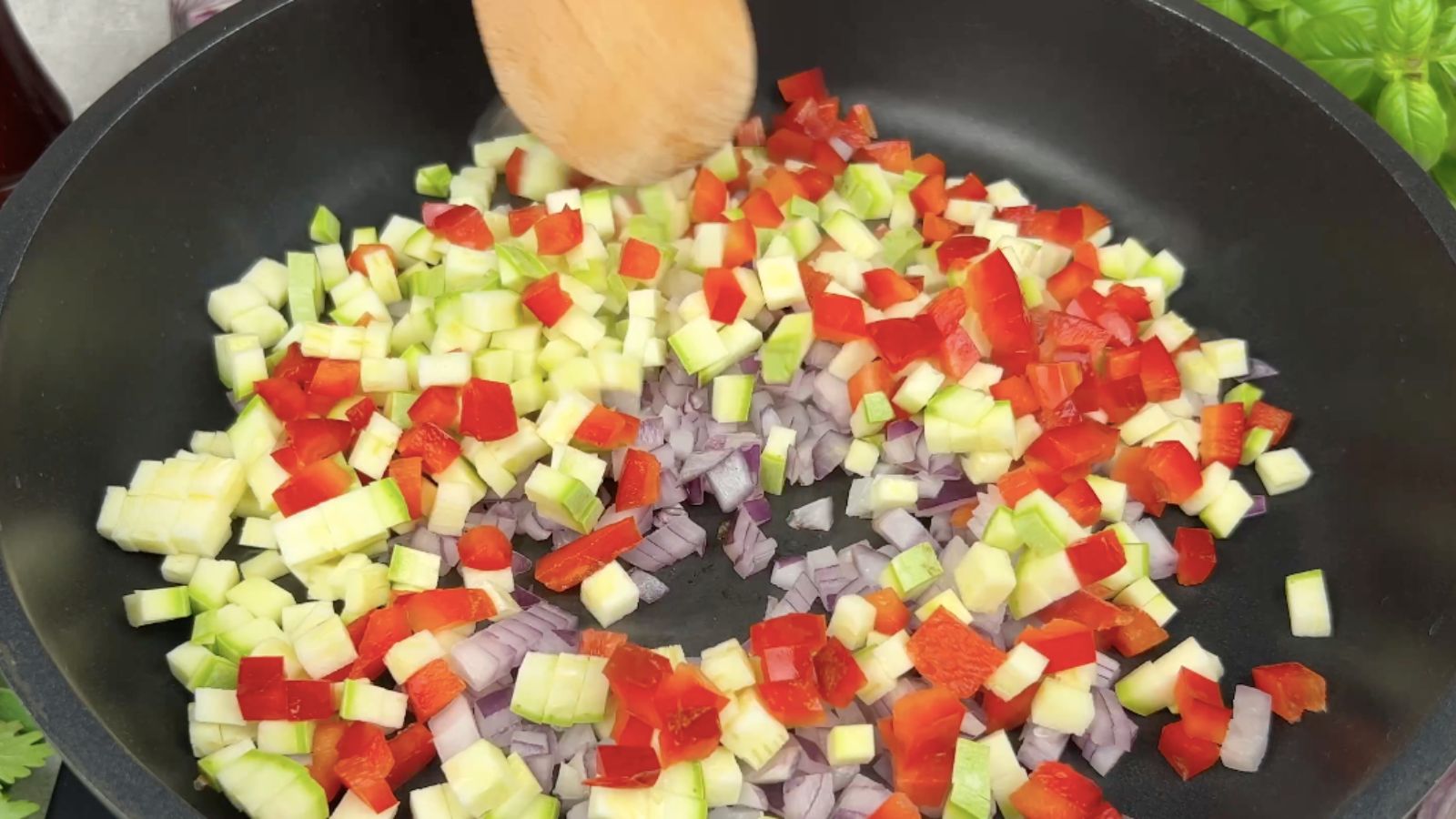 Red onion, red pepper, and zucchini in a skillet.
