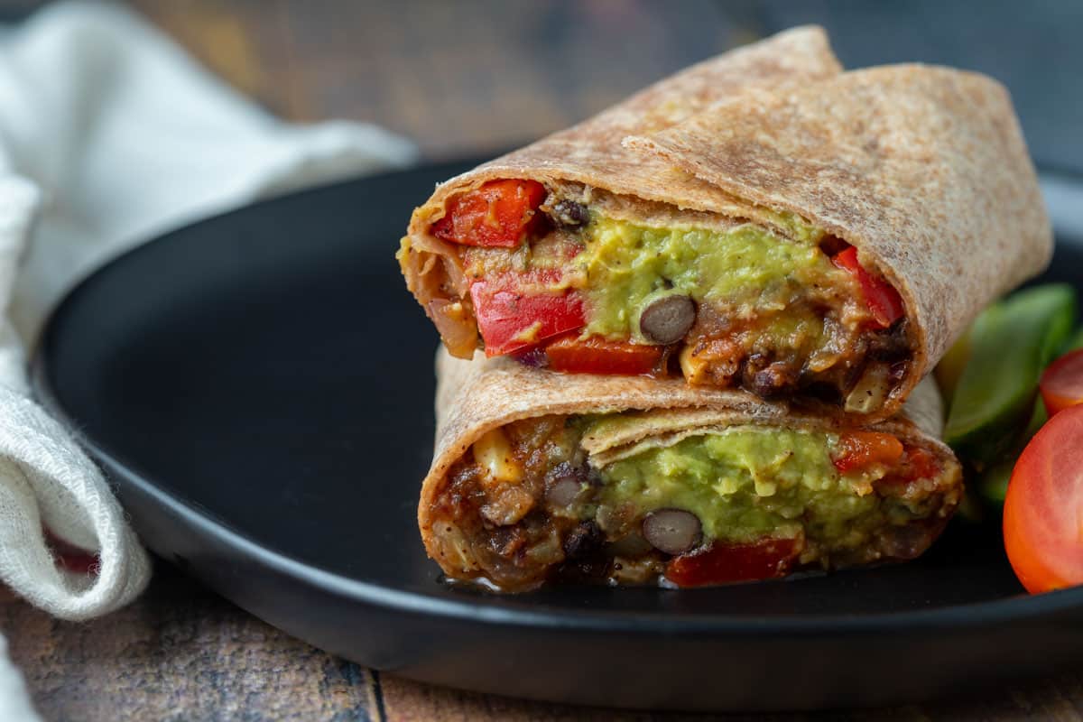 Vegan black bean burrito served on a black plate. 