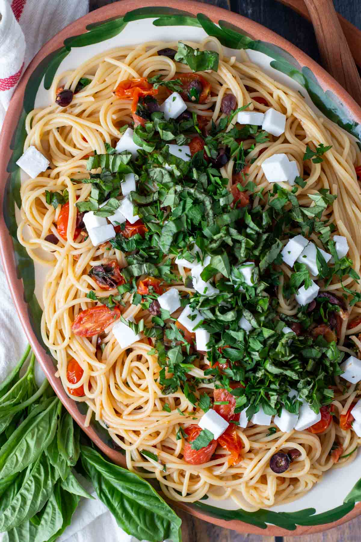 Greek spaghetti topped with fresh herbs and feta cheese cubes.
