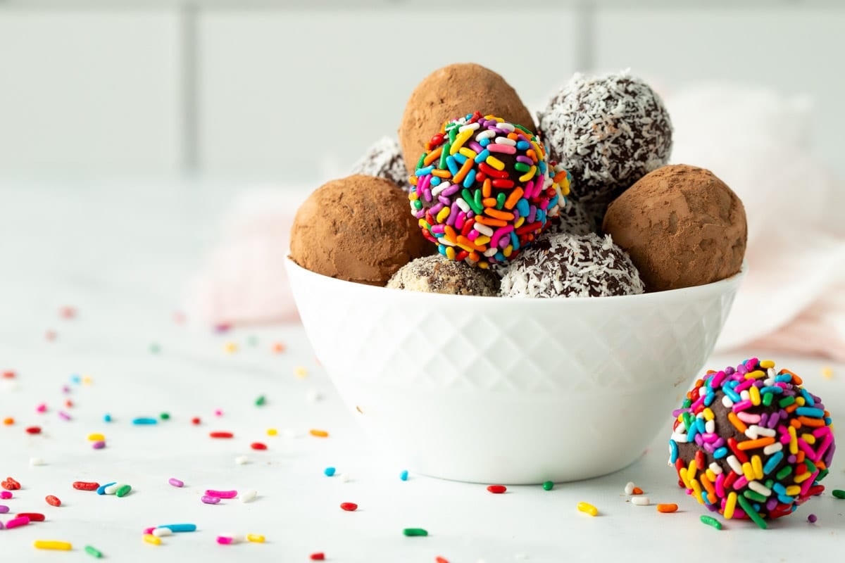 Vegan chocolate truffles in a small white bowl with assorted coatings. 