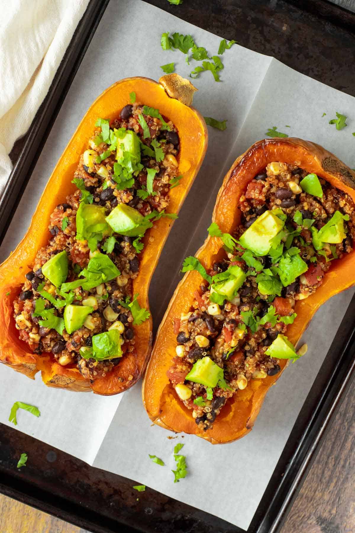 Vegan stuffed butternut squash topped with avocado and cilantro.