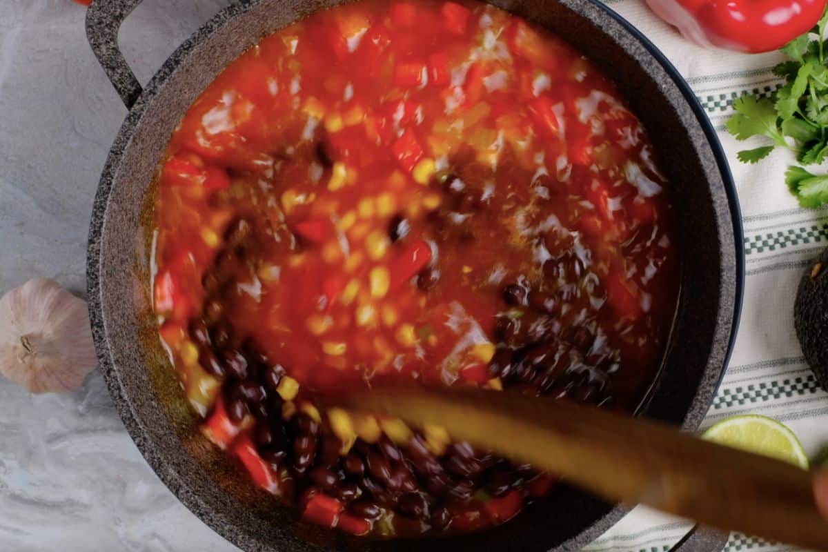 Stirring black beans into pot of tortilla soup.
