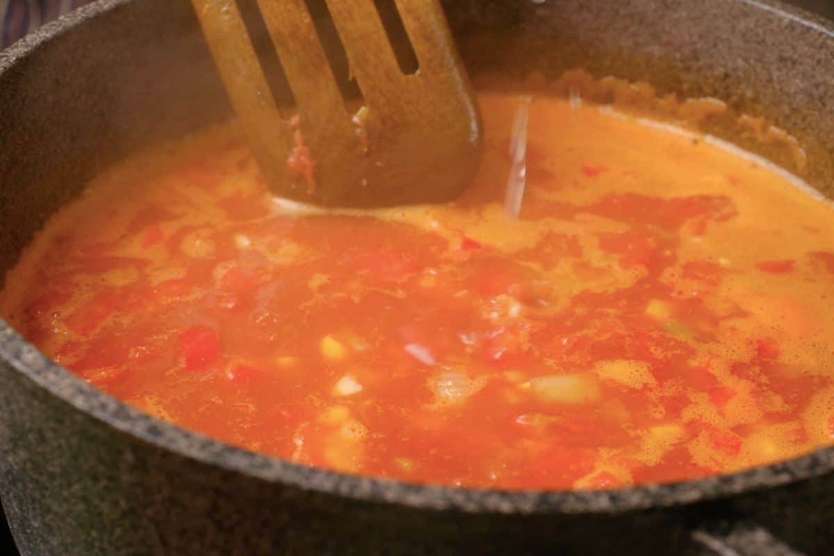 Seasoning pot of tortilla soup with salt.
