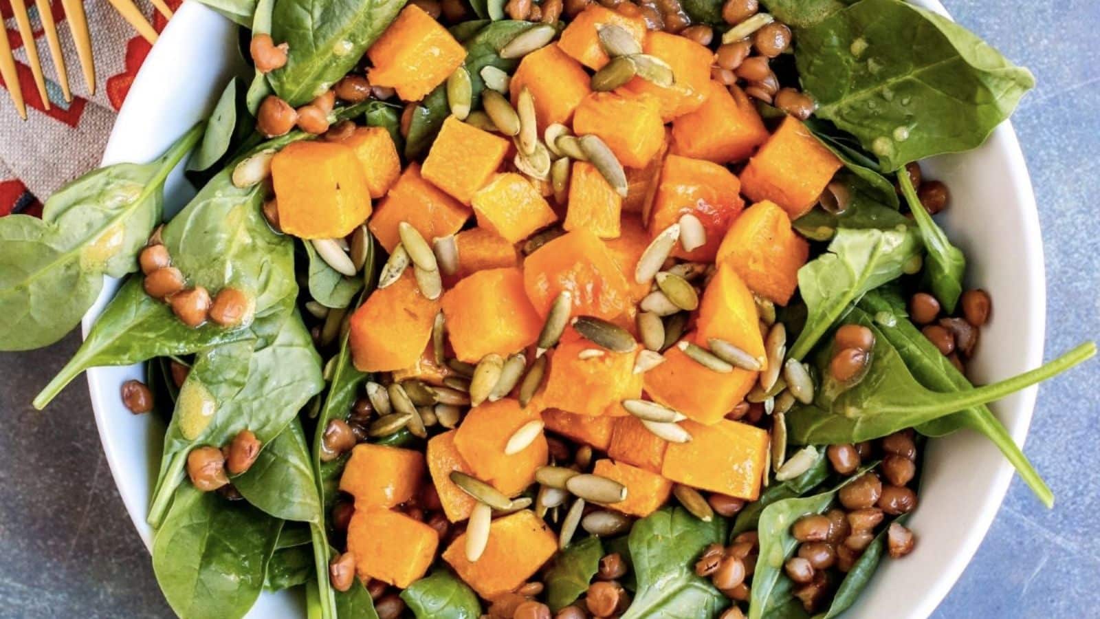 Spinach salad topped with butternut squash and nuts. 