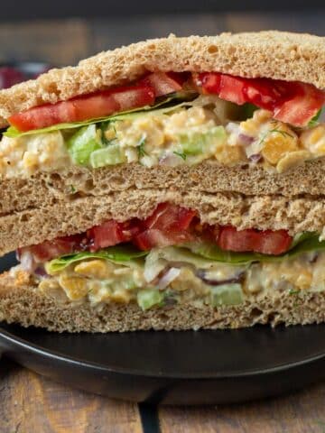 Vegan chicken salad sandwich on black plate.