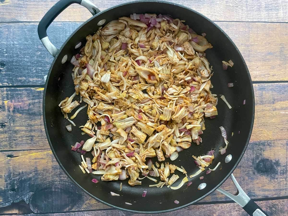 Shredded jackfruit and spices in a saute pan.
