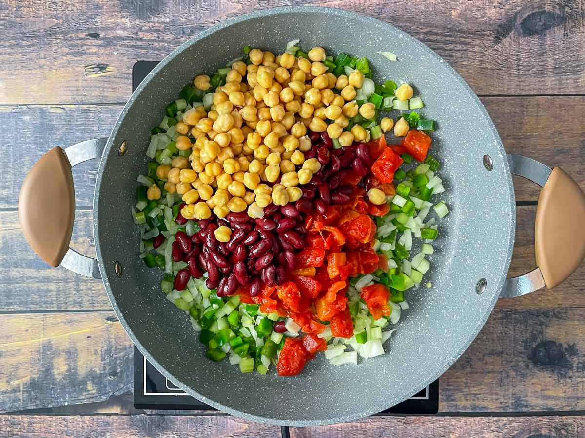Tomatoes, kidney beans, and chickpeas added to saute pan with onions, garlic, celery, and green pepper.
