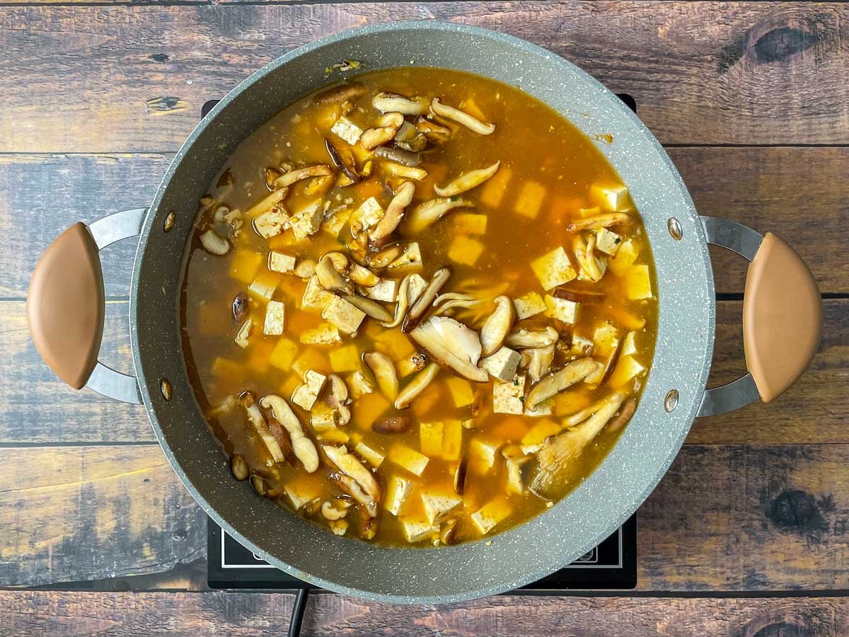 Mushrooms and tofu in a pot with vegetable broth.
